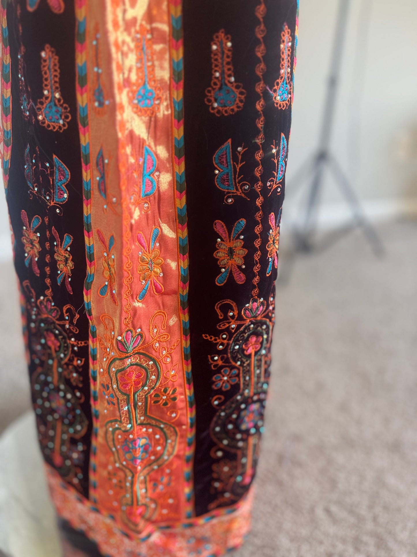 Cream thobe with burgundy velvet and orange satin accents.