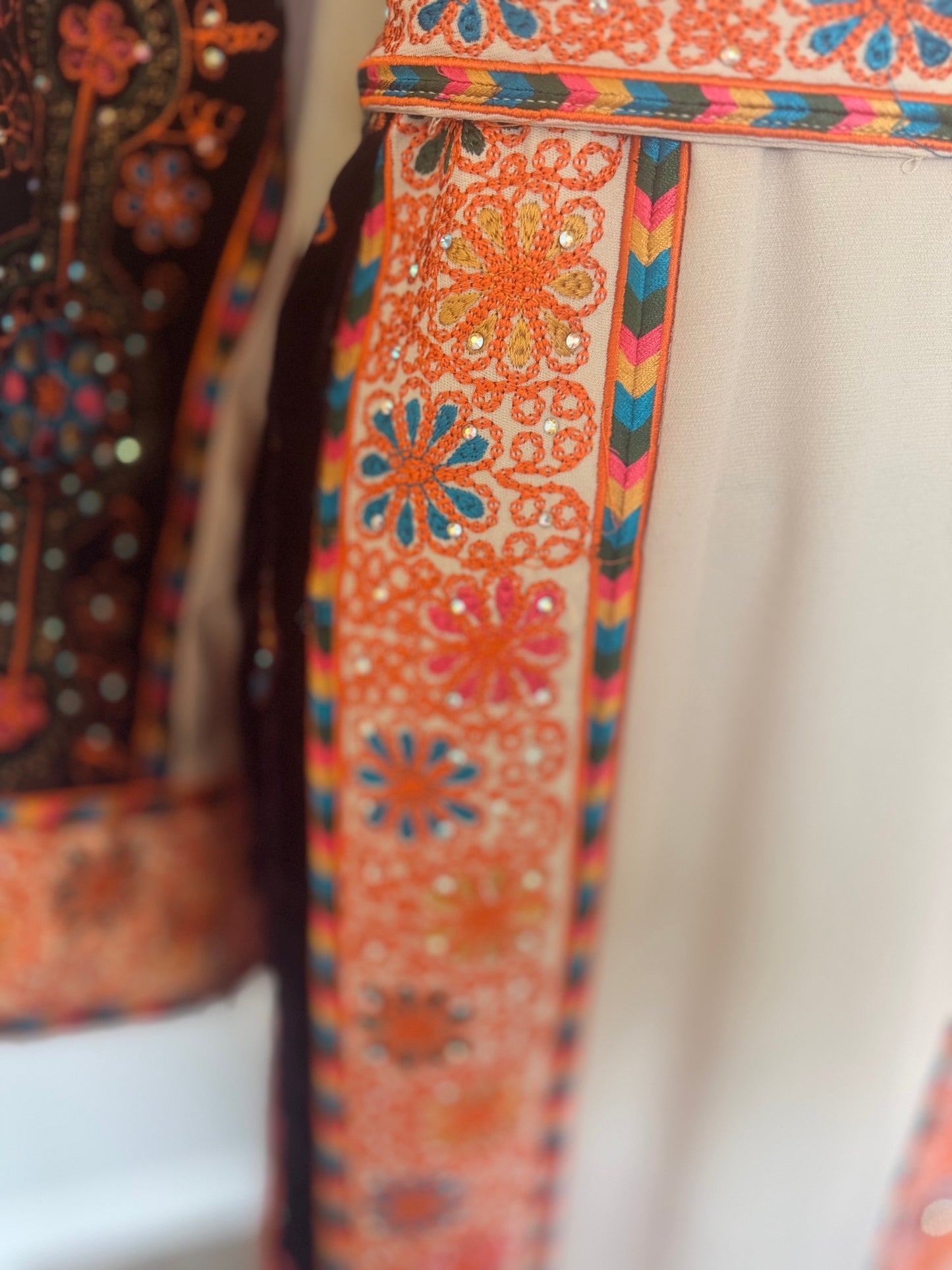 Cream thobe with burgundy velvet and orange satin accents.