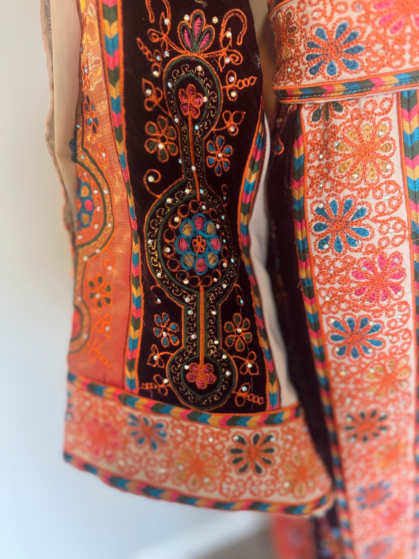 Cream thobe with burgundy velvet and orange satin accents.