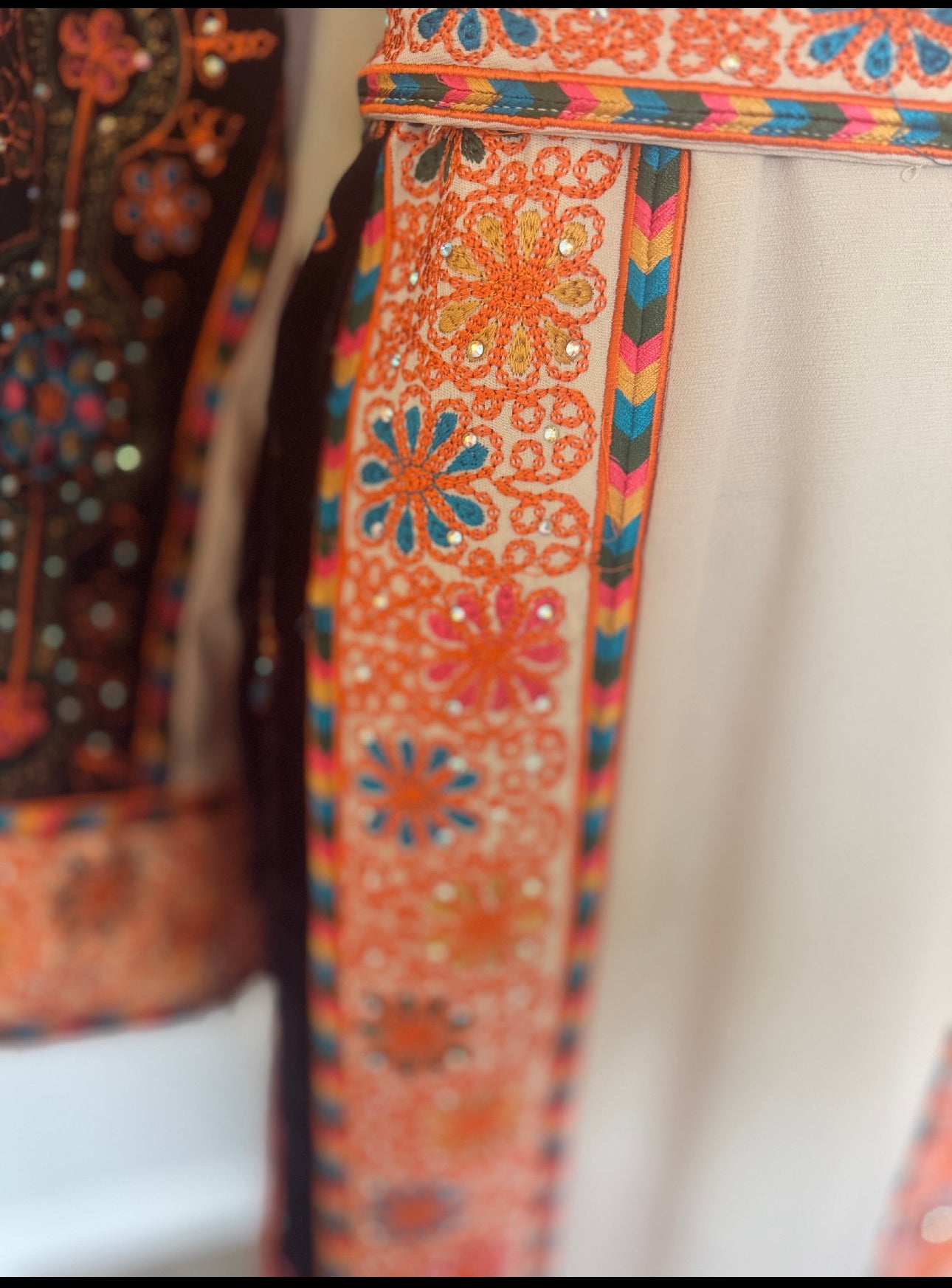 Cream thobe with burgundy velvet and orange satin accents.