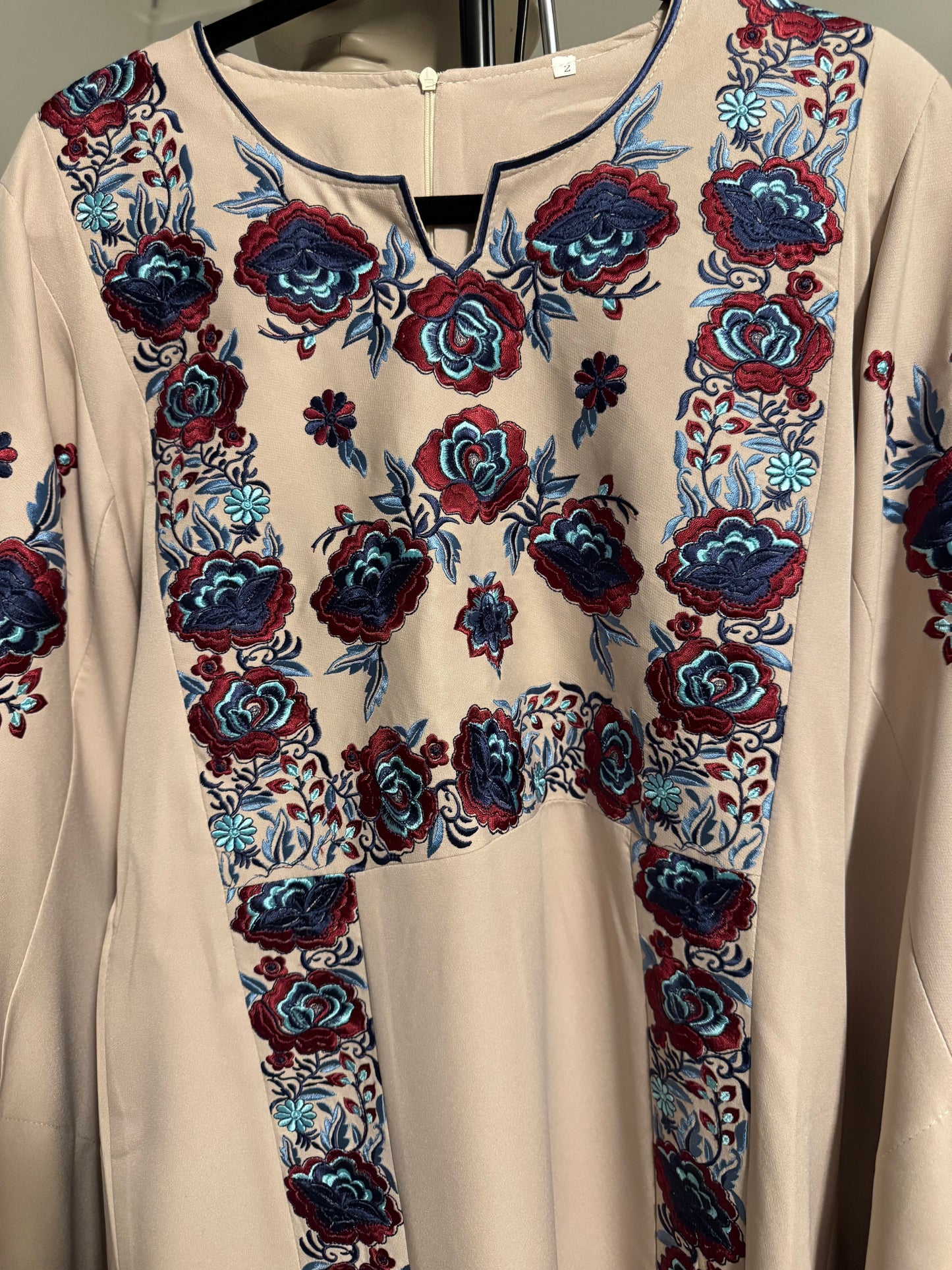 Beige -colored fabric thobe with blue embroidery.