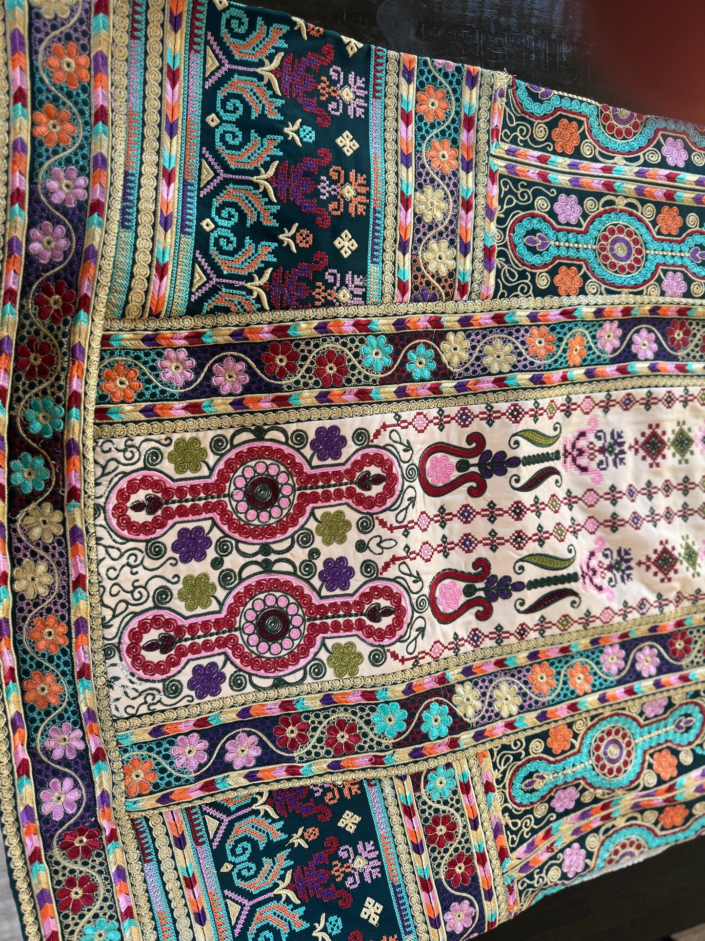 Light beige thobe with green fabric and colorful embroidery.