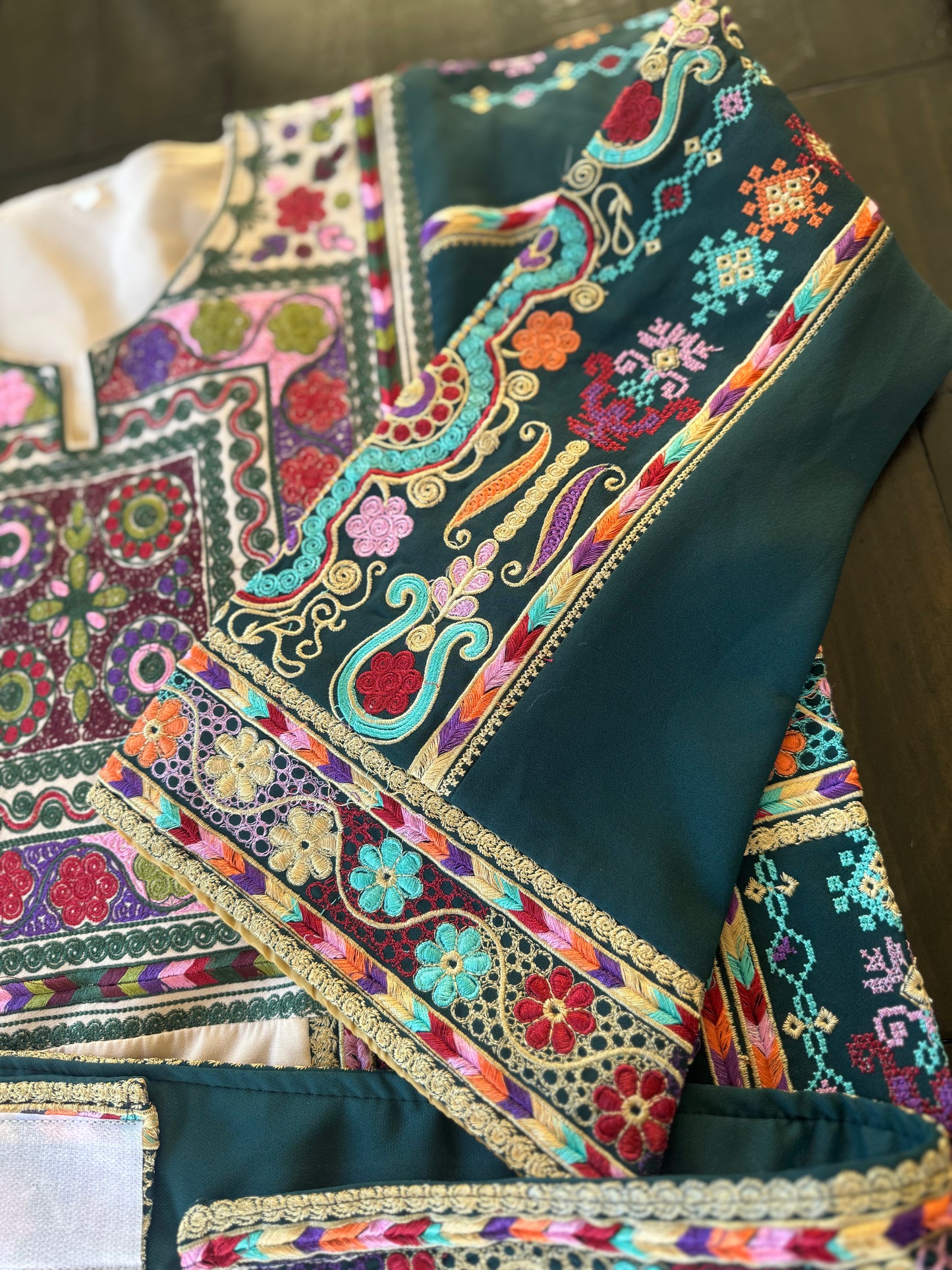 Light beige thobe with green fabric and colorful embroidery.