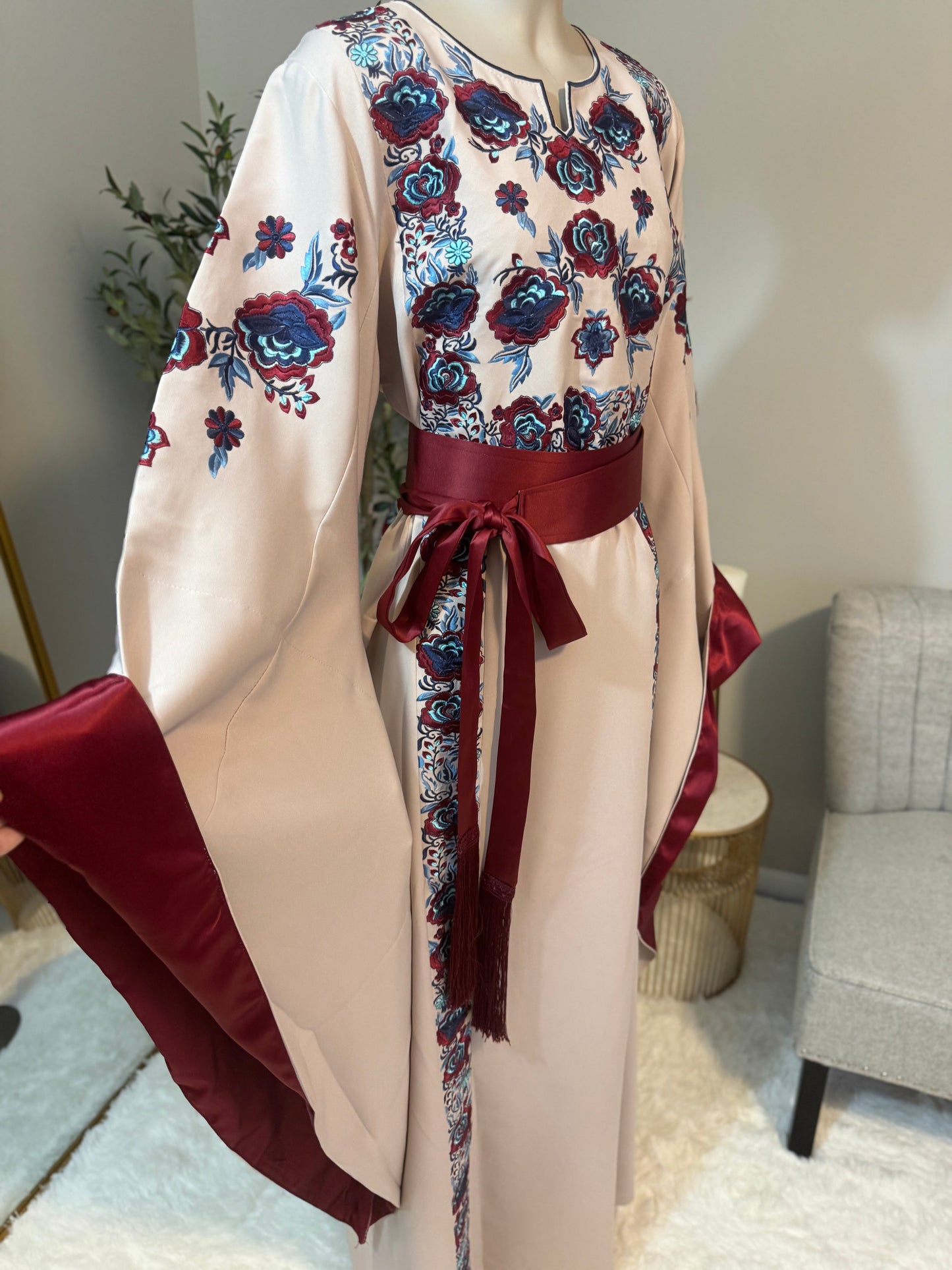 Beige -colored fabric thobe with blue embroidery.