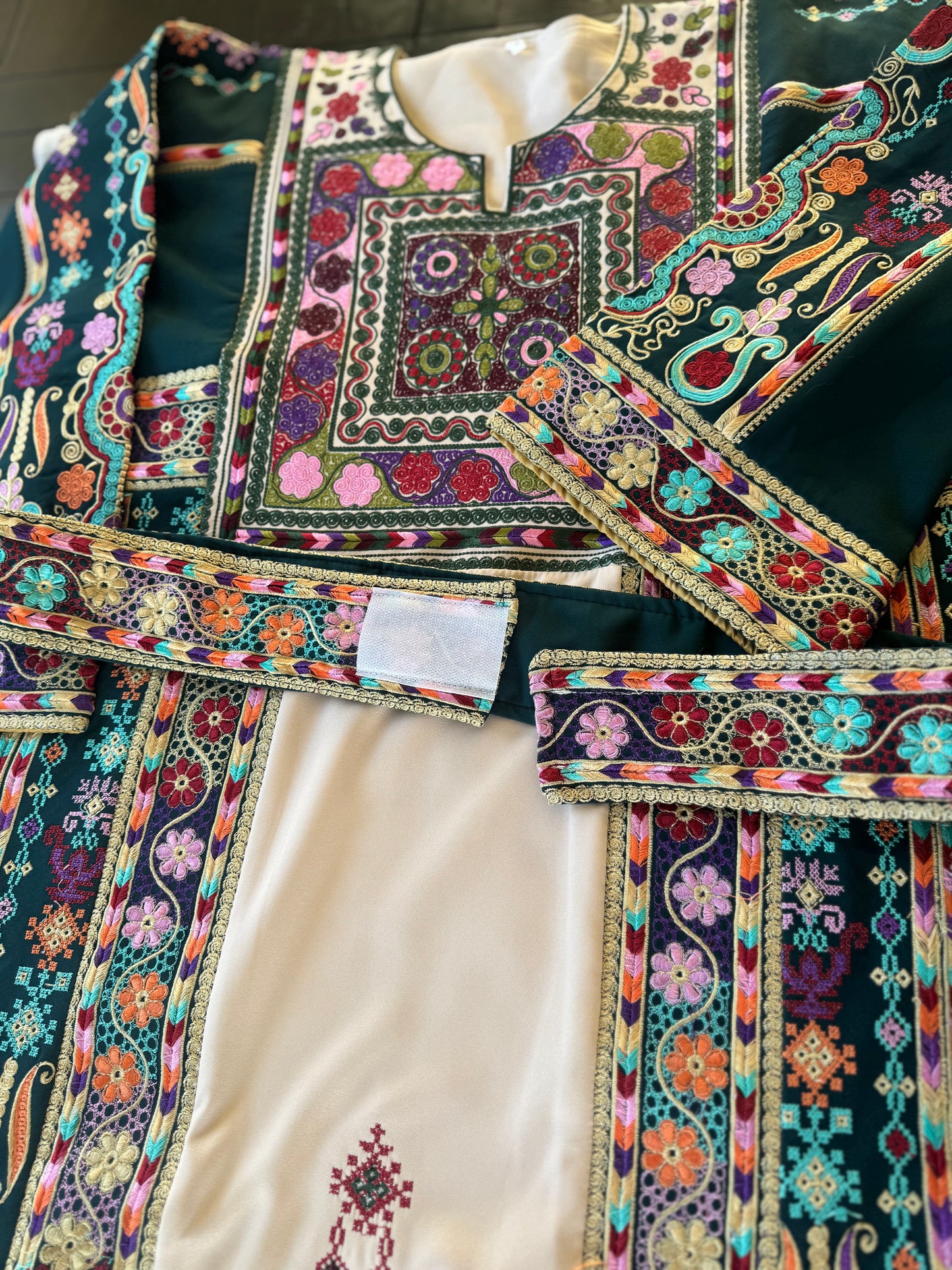 Light beige thobe with green fabric and colorful embroidery.