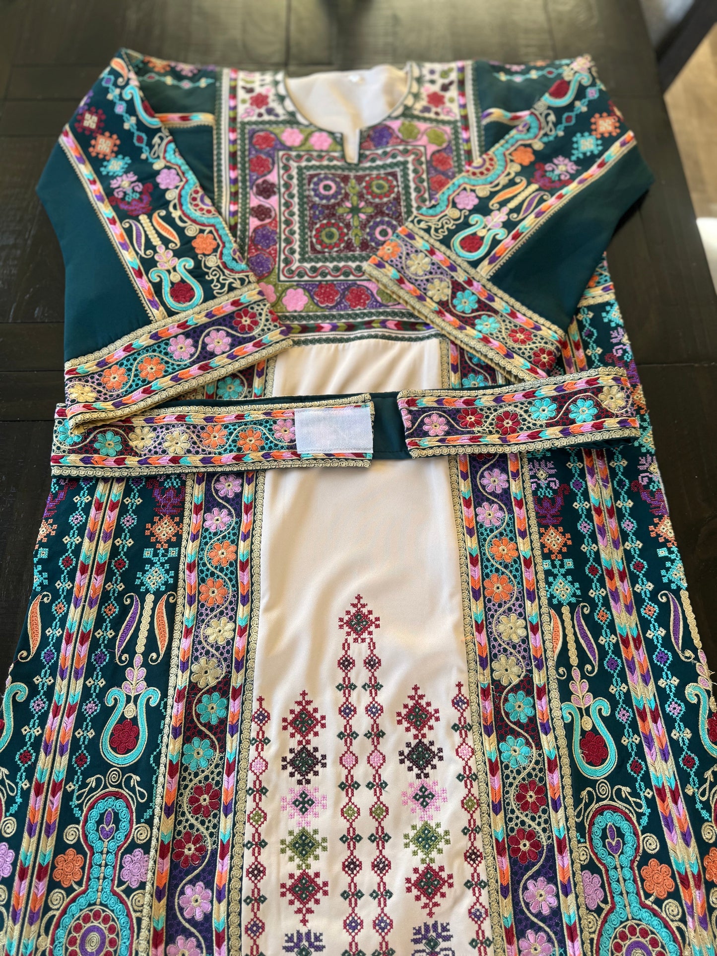 Light beige thobe with green fabric and colorful embroidery.